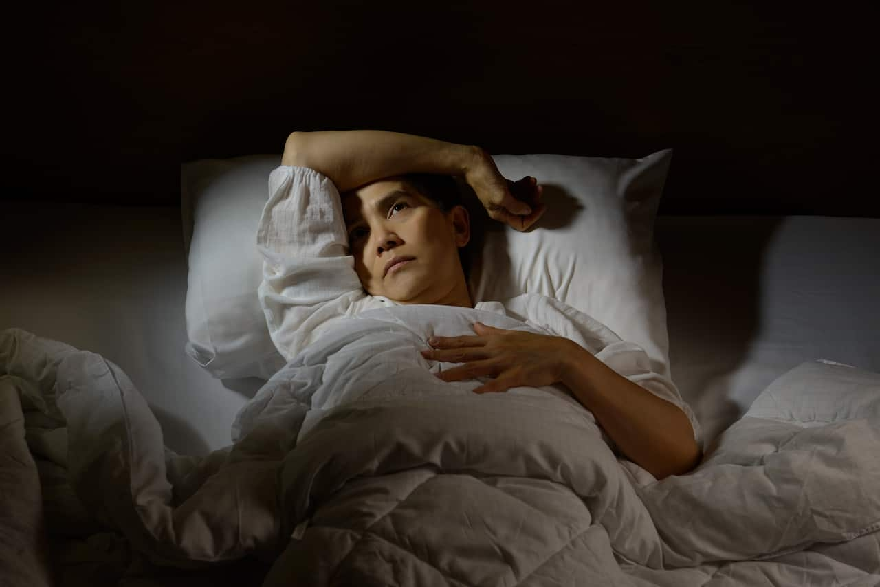 A woman laying in bed with eyes open