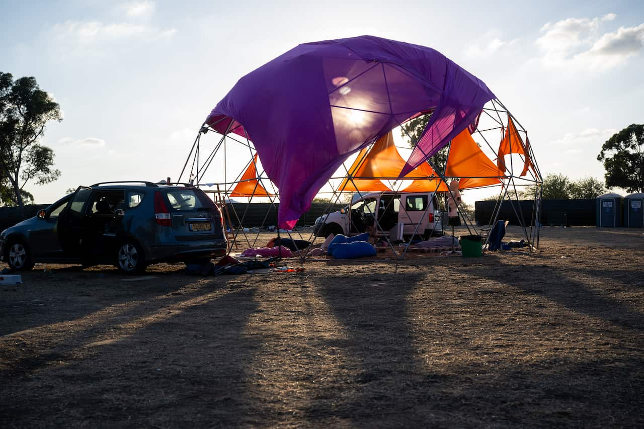 A dome structure covered in ripped colourful fabric.