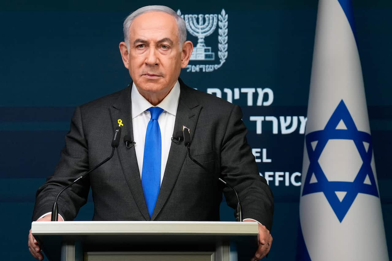 A man in a suit stands at a lectern.