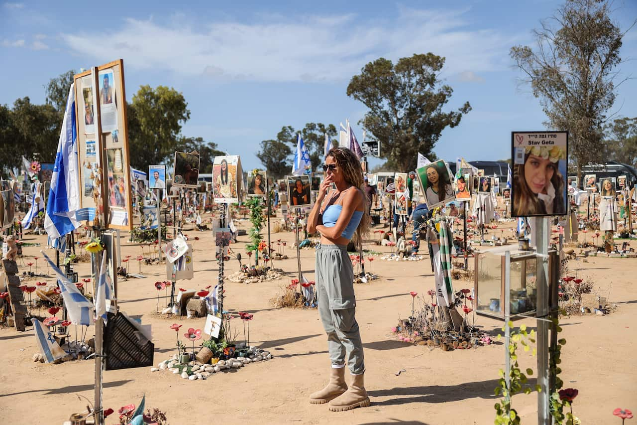 A woman stands around pictures at a memorial