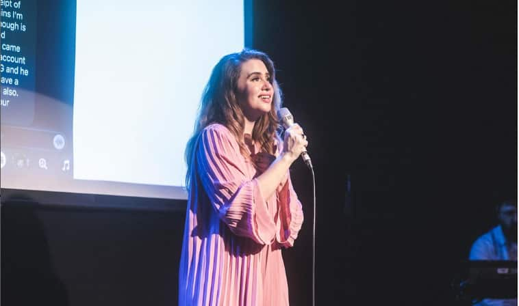 A woman in a pink dress singing on stage