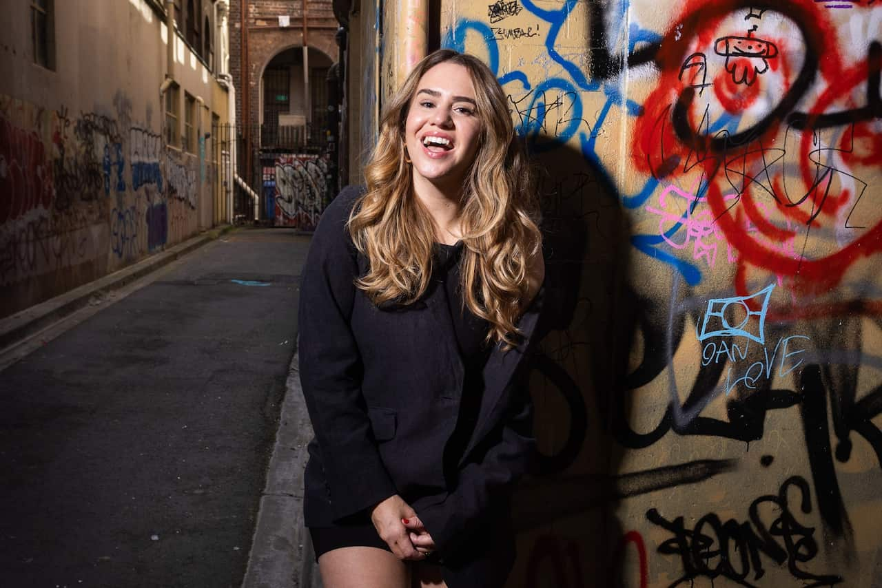 A woman posing against a graffitied wall