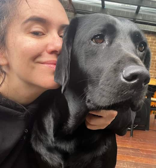 A woman hugging a black labrador 